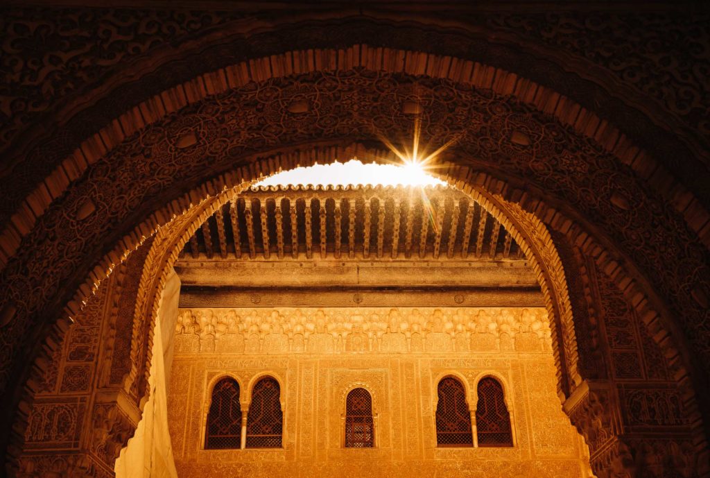 Die Sonne blitzt durch den Torbogen in der Alhambra in Granada.