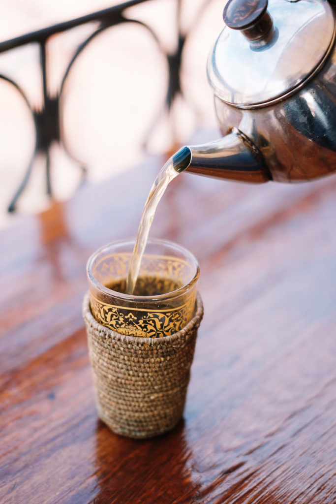 Tee wird auf der Dachterrasse eines Cafes in Marrakesch eingeschenkt.
