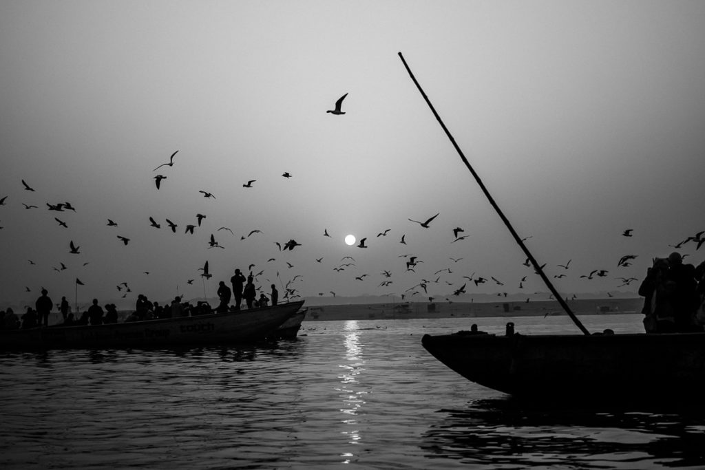 Sonnenaufgang in Varanasi am Ganges. Vögel und Boote begrüßen den Tag.