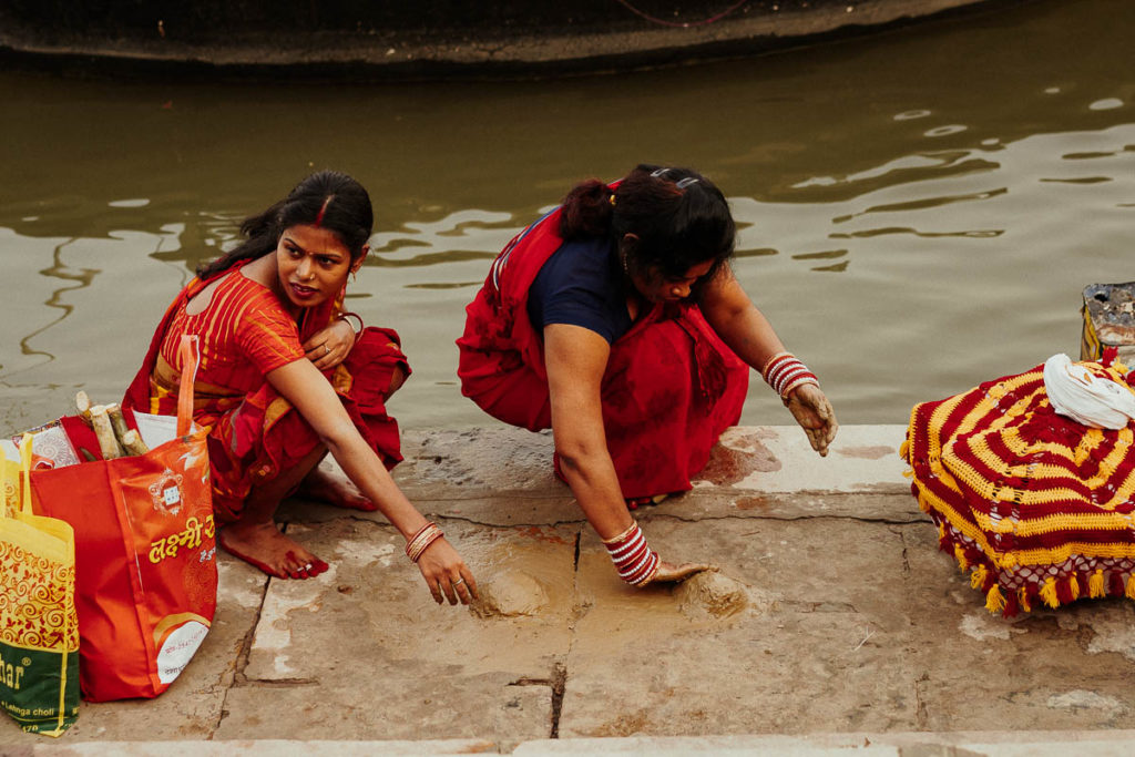 Aus Lehm bauen die Frauen am Ganges kleine Häufchen, in die sie später Räucherstäbchen stecken und entzünden.