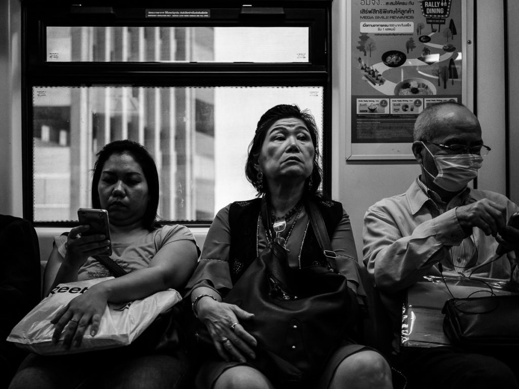 Drei Menschen im Skytrain in Bangkok