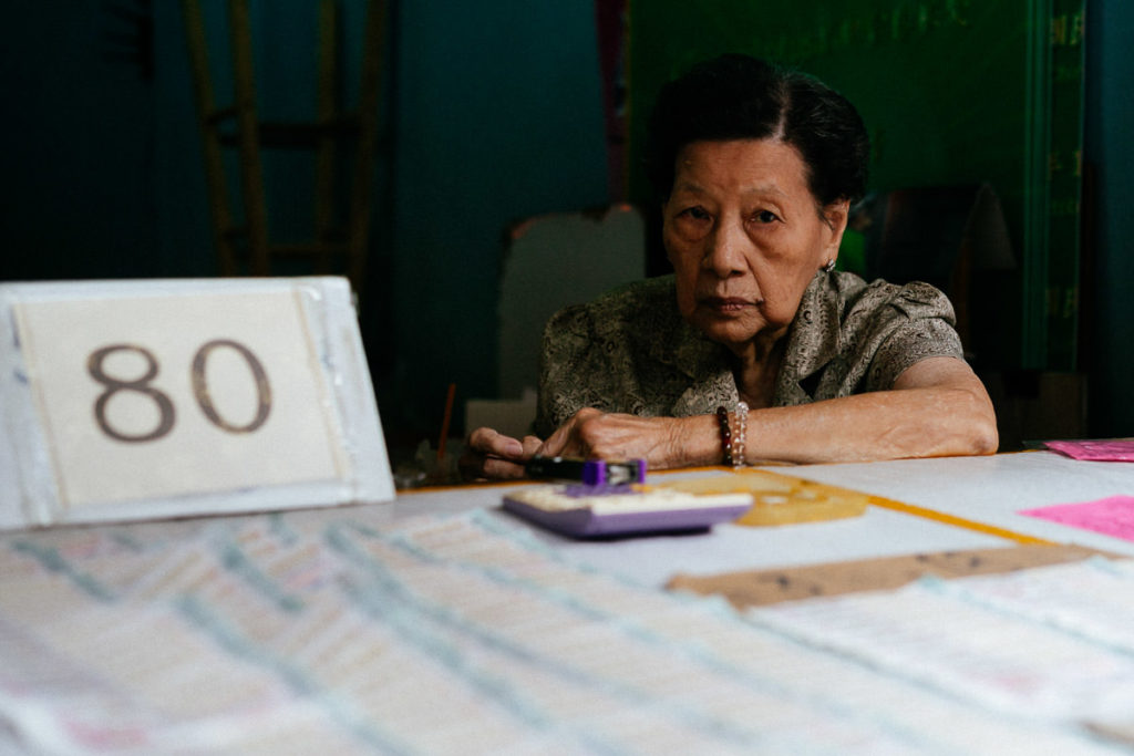 Frau schaut über ihren Tresen in Bangkoks Chinatown