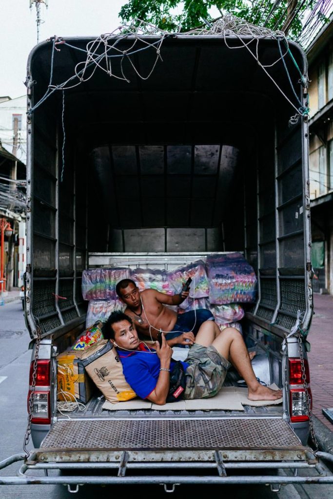 Pause im Kleinlaster: zwei Männer machen liegend Rast im hinteren Teil ihres Fahrzeugs