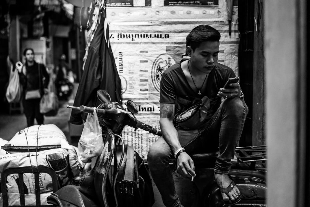 Mann sitzt auf seinem Motorrad und schaut auf sein Handy