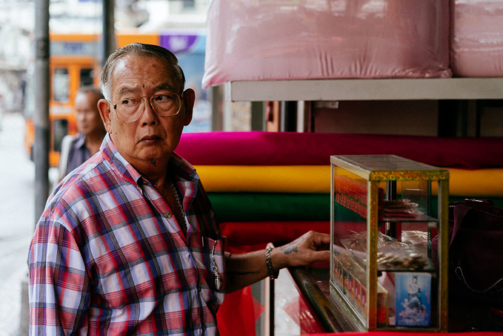 Stofffachhandel in Bangkok, ein Mann schaut argwöhnisch auf die Straßen von Chinatown