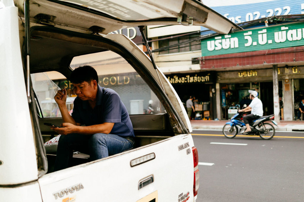 Blick in einen kleinen Lastentransporter; ein Mann schaut auf sein Handy