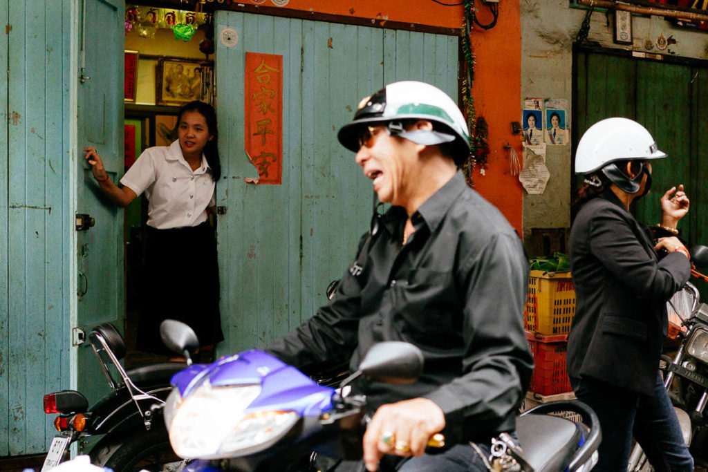 Straßenszene in Rattanakosin, Bangkok. Ein Mann fährt mit seinem Motoroller durch die Straße