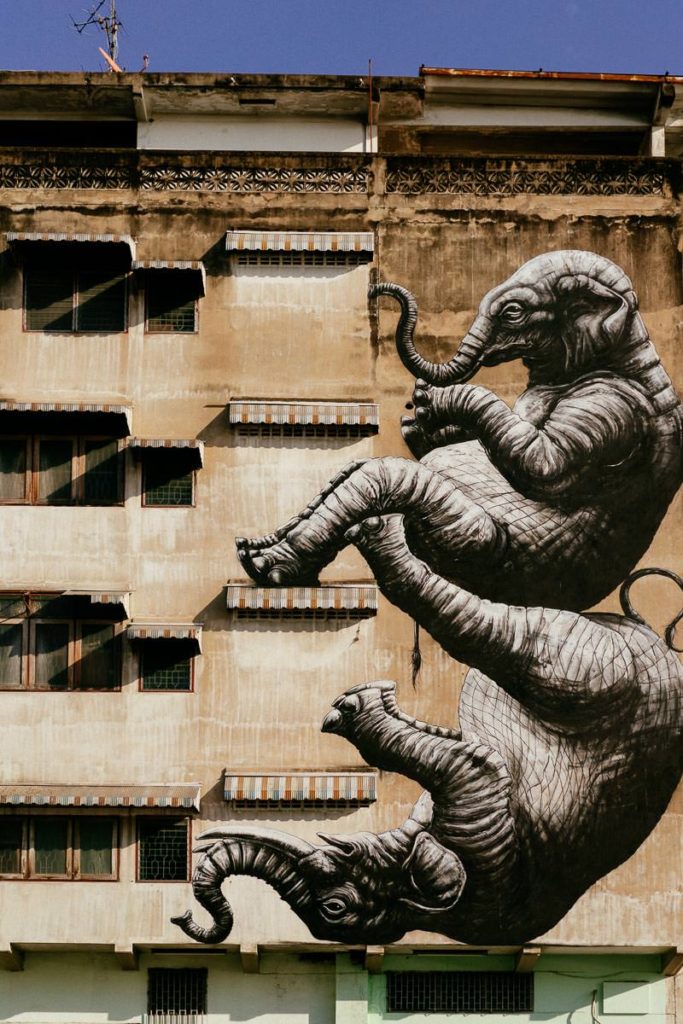 Wandmalerei in Talat Noi in Bangkok. Es zeigt zwei Elefanten, die turnen, an einer Hauswand.