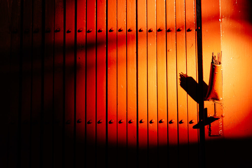 Rote Wand wird von Sonne beschienen, an der rechten Seite sind Räucherstäbchen befestigt.