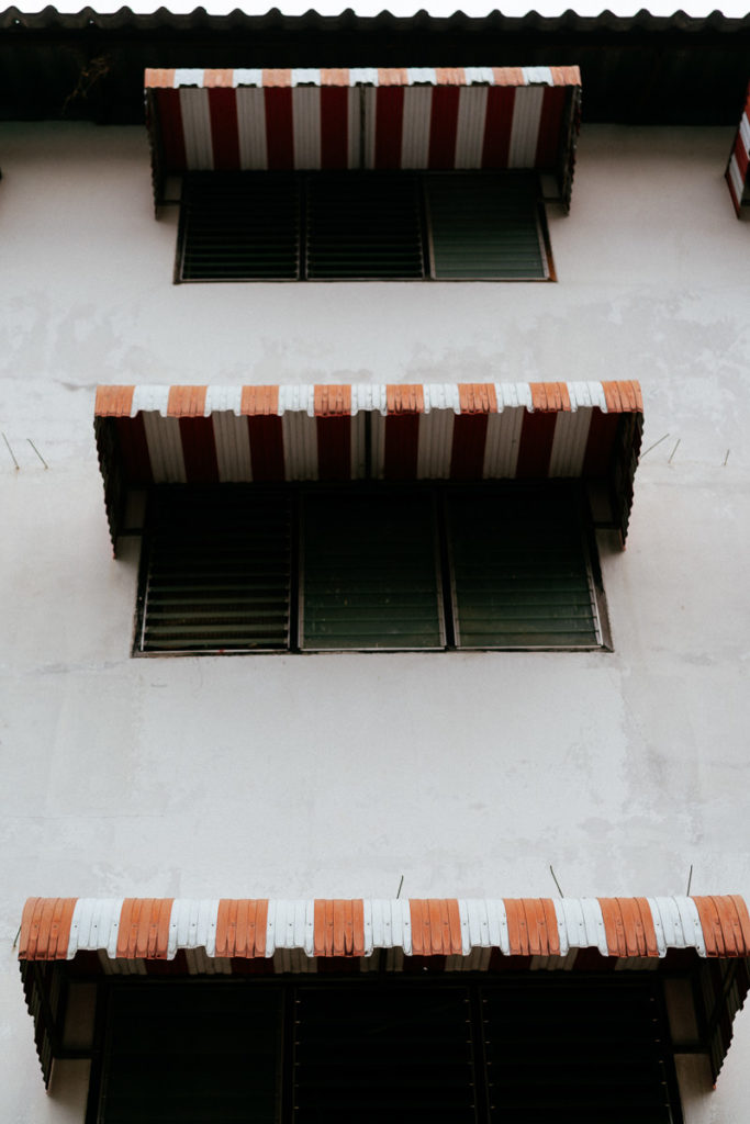 rot-weiß gestreifte Markisen an Fenstern eines weißes Hauses