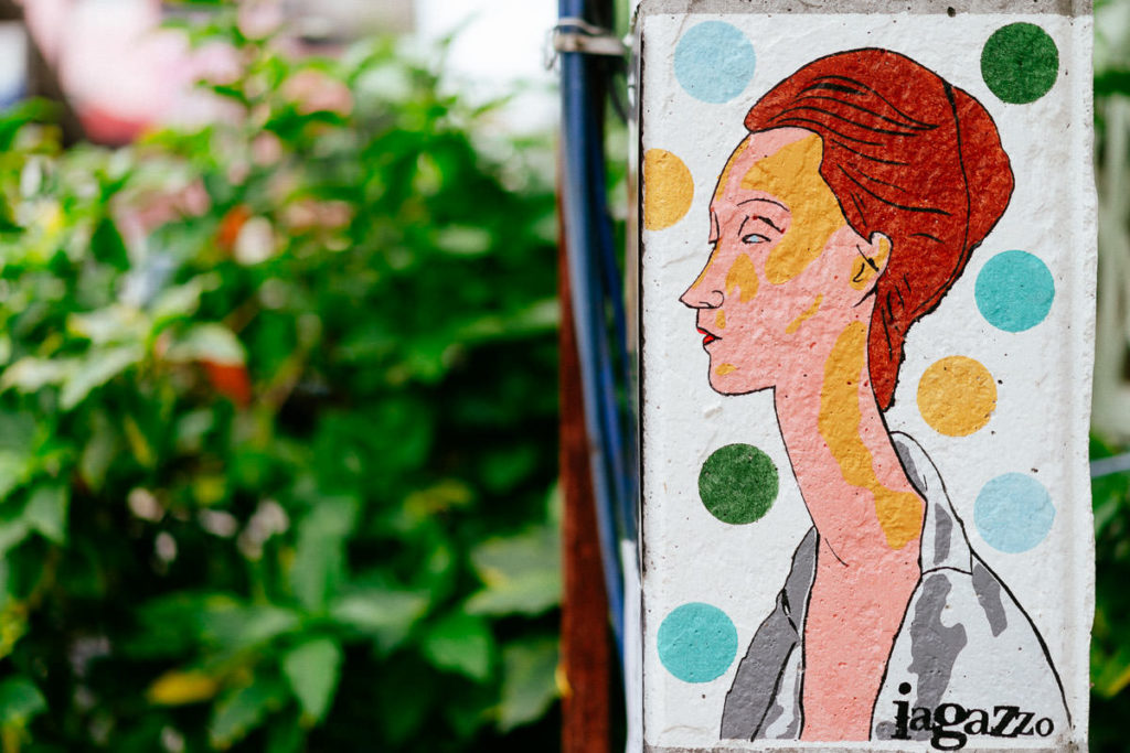 Iagazzo Graffiti einer kurzhaarigen Frau auf weißem Hintergrund mit bunten Punkten